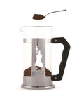 French press coffee maker with a spoonful of coffee grounds on a white background