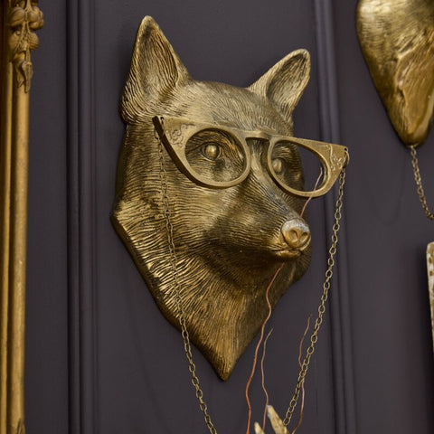 Gold fox head with glasses on a dark purple wall