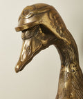 Bronze sculpture of a duck's head on a plain background