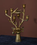 Bronze candelabrum with multiple candle holders on a dark surface against a brown background
