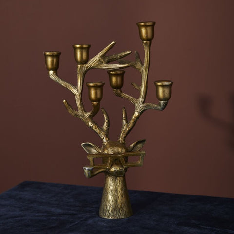 Bronze candelabrum with multiple candle holders on a dark surface against a brown background