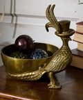 Brass bird-shaped container with decorative items on a wooden surface