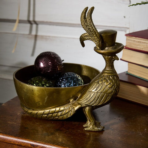 Brass bird-shaped container with decorative items on a wooden surface