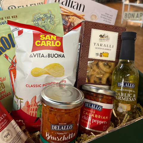 Assorted Italian food products including chips, olives, and tomato bruschetta in a box.