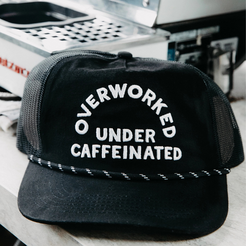 Overworked Under Caffeinated Trucker Hat by Pyknic