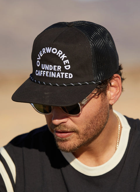 Overworked Under Caffeinated Trucker Hat by Pyknic