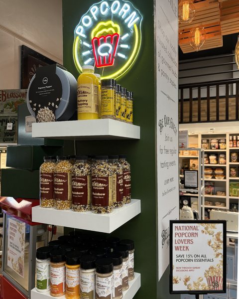 Popcorn seasoning display with neon sign and shelf in a store setting