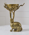 Brass rabbit-shaped holder with bowl on a white surface and light gray background