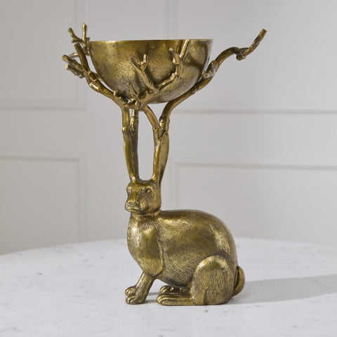 Brass rabbit-shaped holder with bowl on a white surface and light gray background