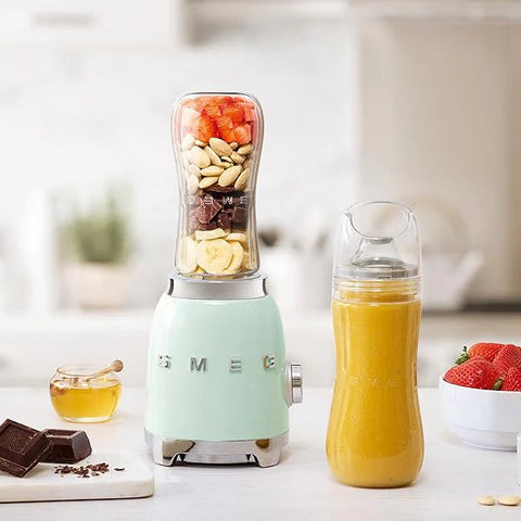 Smeg blender with ingredients and a smoothie on a kitchen counter